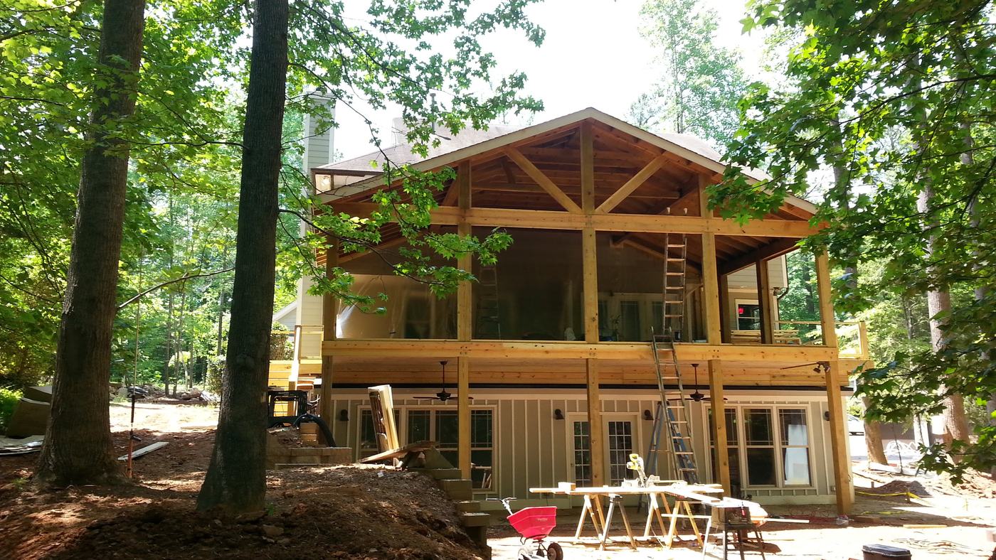 Timber-frame porch rising on the back of the house among tall trees