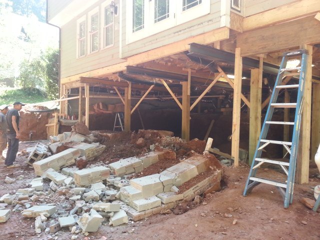 The old back deck torn out, with broken concrete and a ladder under the house during the crawlspace dig-out