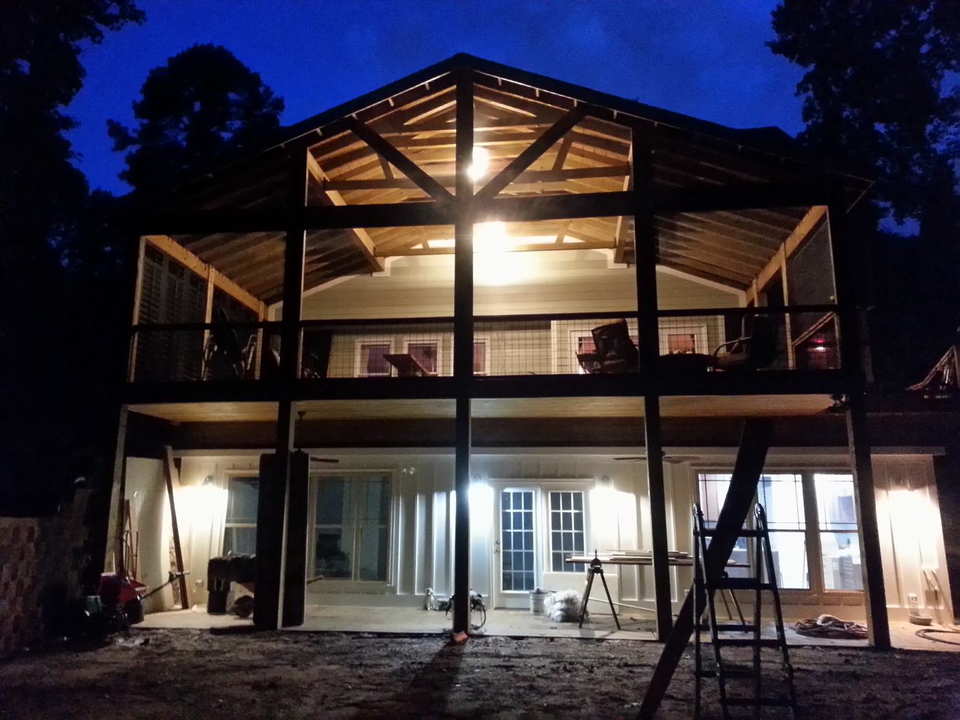 The new two-level timber-frame screened porch on the back of the house, lit up at night