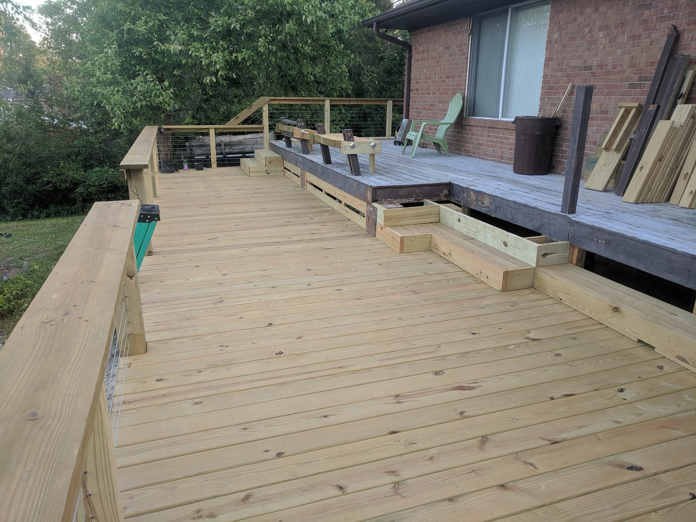 Large new pressure-treated deck with built-in benches along a brick house