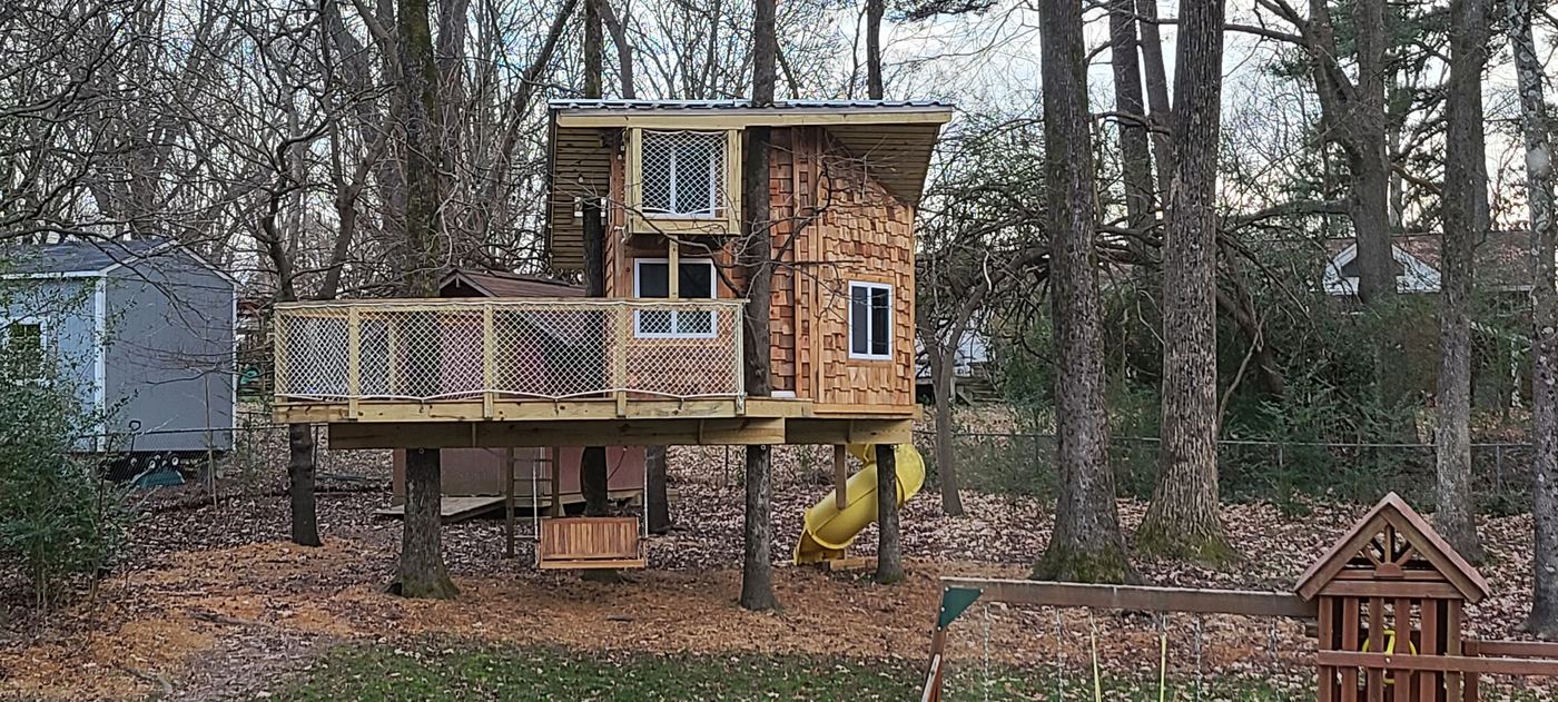The finished treehouse set among the trees at the back of the yard